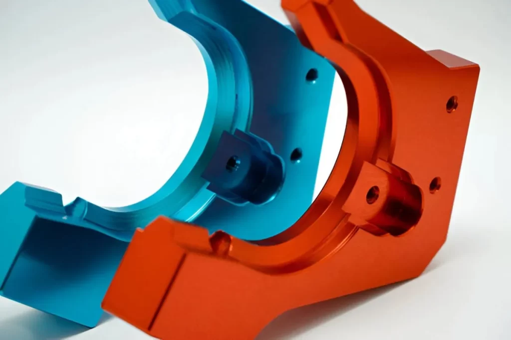 The image shows a pair of anodized aluminium parts in red and blue, with the same design.