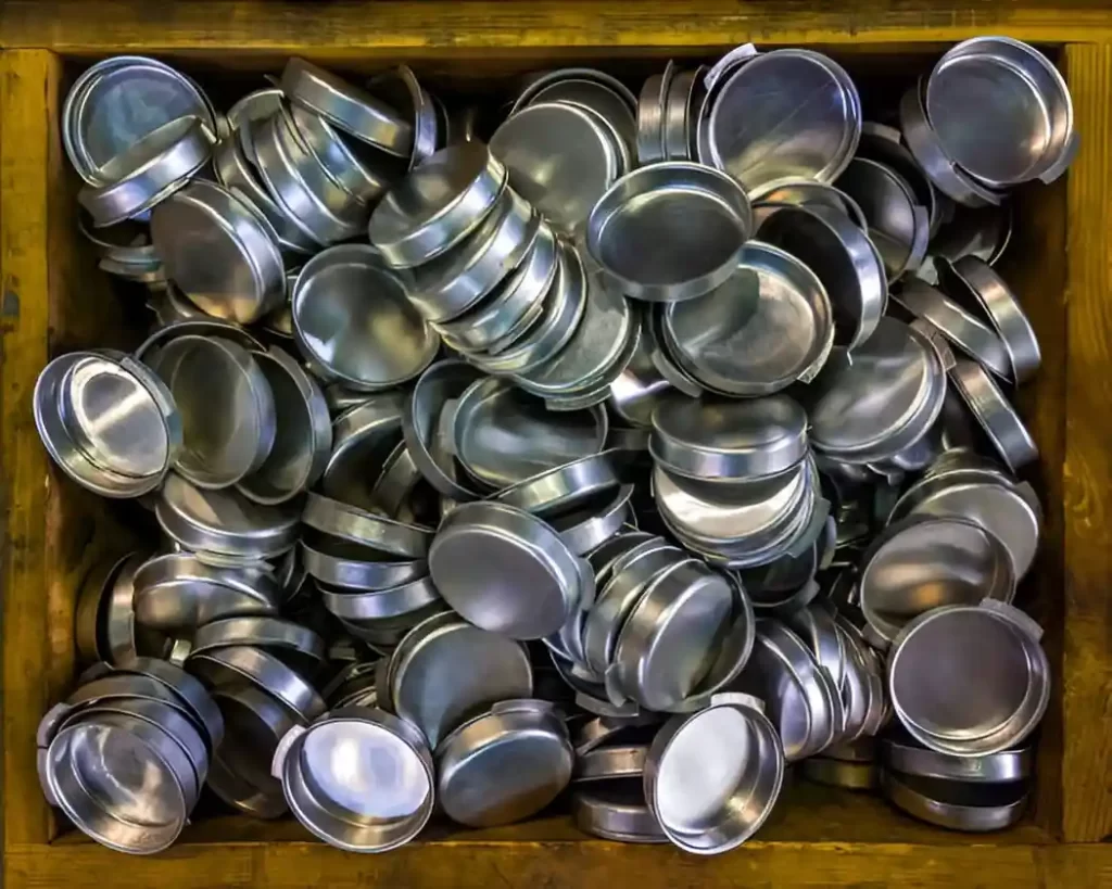 Deep-drawn aluminum parts are placed neatly inside a bucket.