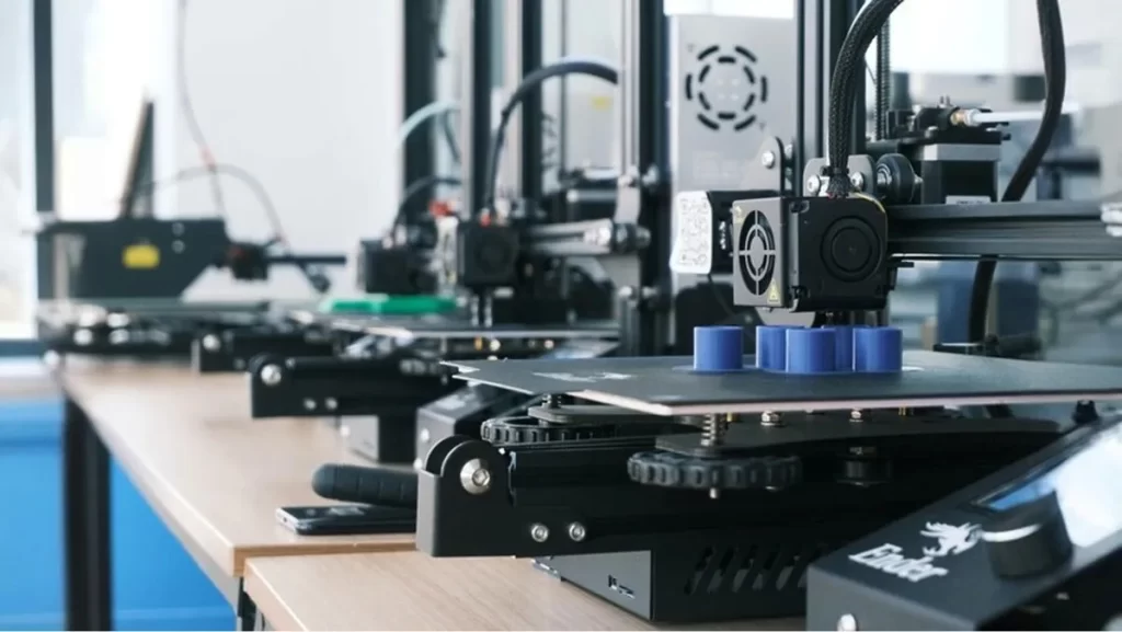 Row of 3D printers producing blue plastic parts.