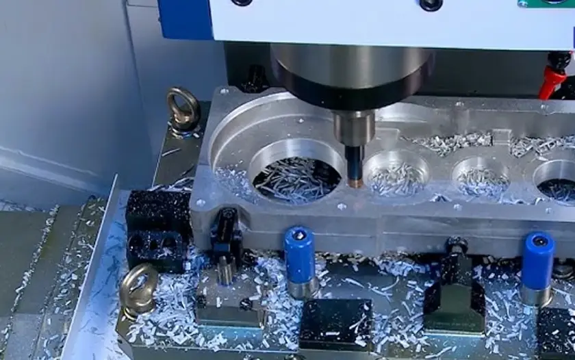 Milling tool on a VMC creating precision holes in a recessed section of a metal block
