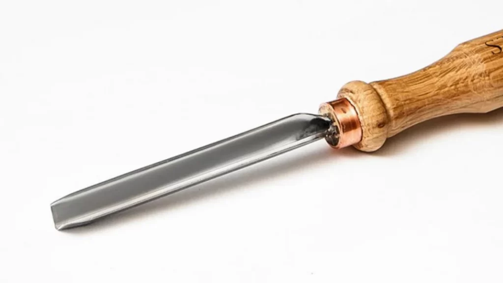 A close-up image of a parting tool used in machining. The tool has a narrow, flat cutting edge designed to cut off sections of a workpiece on a lathe. 
