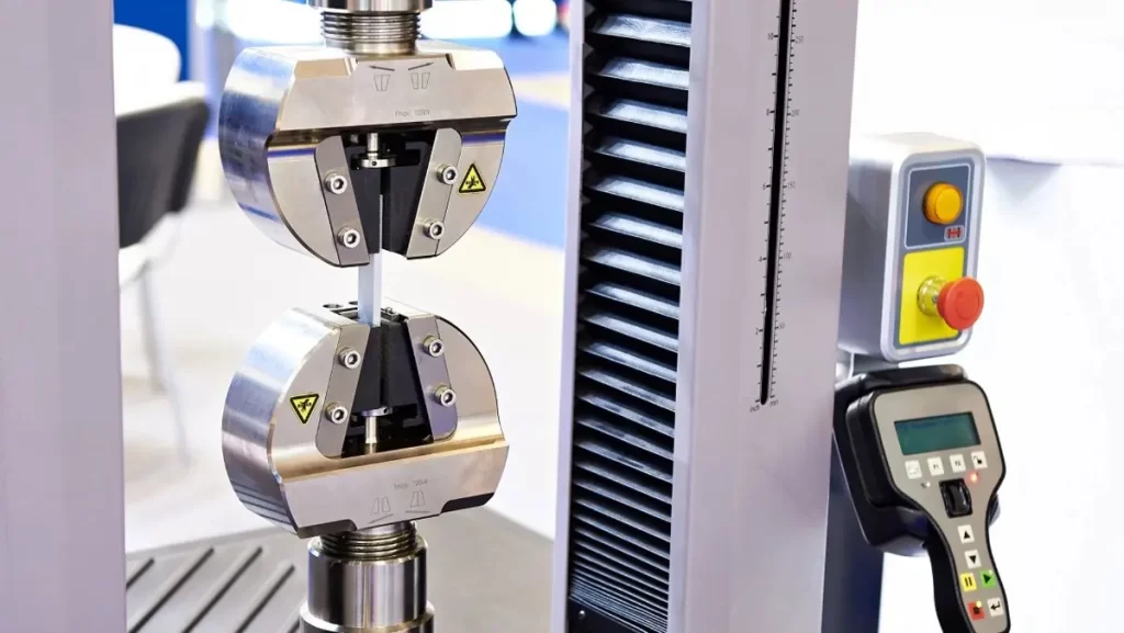 Tensile testing machine gripping a white material sample.