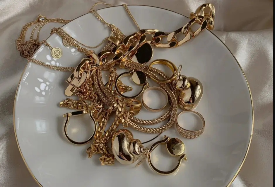 Golden bracelets, necklaces and other jewelry of the metal placed on a white plate 