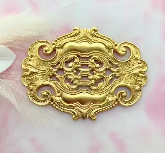 A golden-colored shape created by Brass Stamping with a light pink background