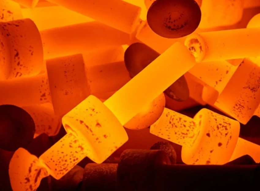 Glowing orange metal parts undergoing heat treatment at high temperatures