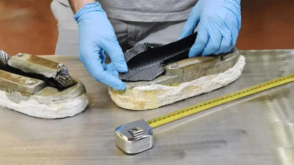 A person wearing blue gloves is assembling a carbon fiber part