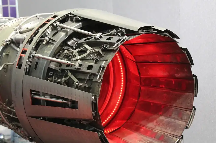 Close-up of an aircraft jet engine nozzle with visible fasteners and glowing red interior, suggesting high heat or afterburner effect