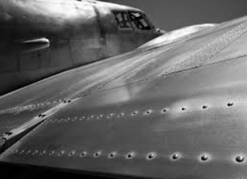 A closeup image of a gray aircraft wing with several lines of rivets