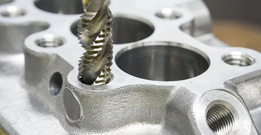 A close view of the CNC drill bit creating a hole on the zinc workpiece 