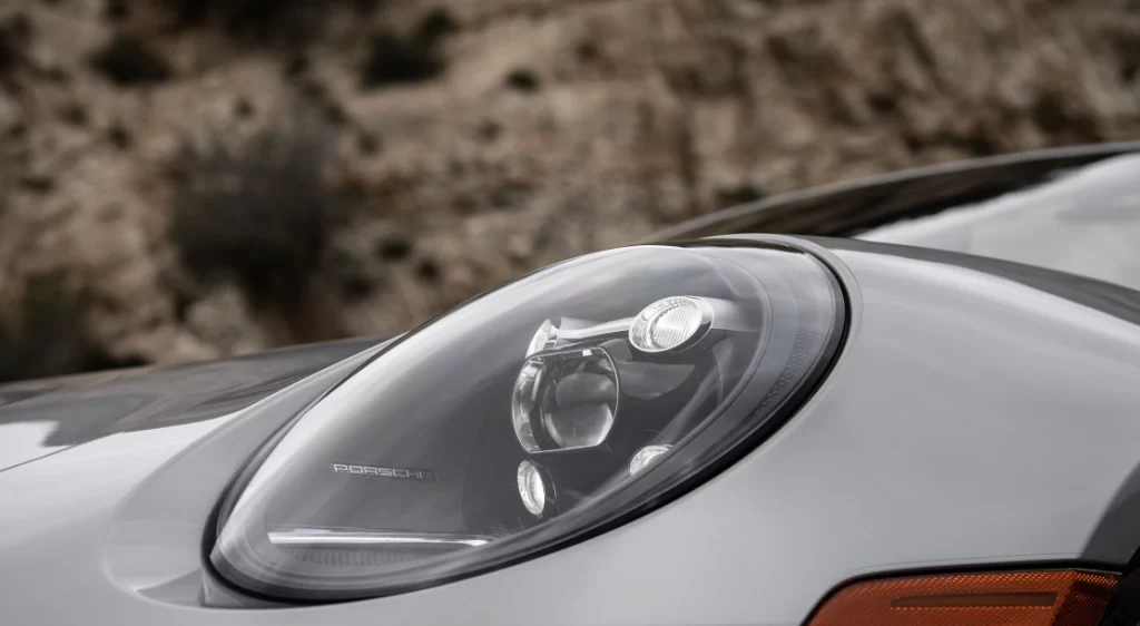 Close-up of a Porsche headlight with adaptive lighting desiggn against a blurred stone wall background