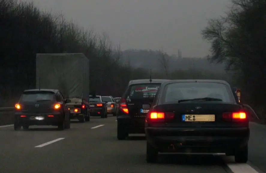 Traffic jam on a highway during overcast conditions with cars showing hazard lights illuminated