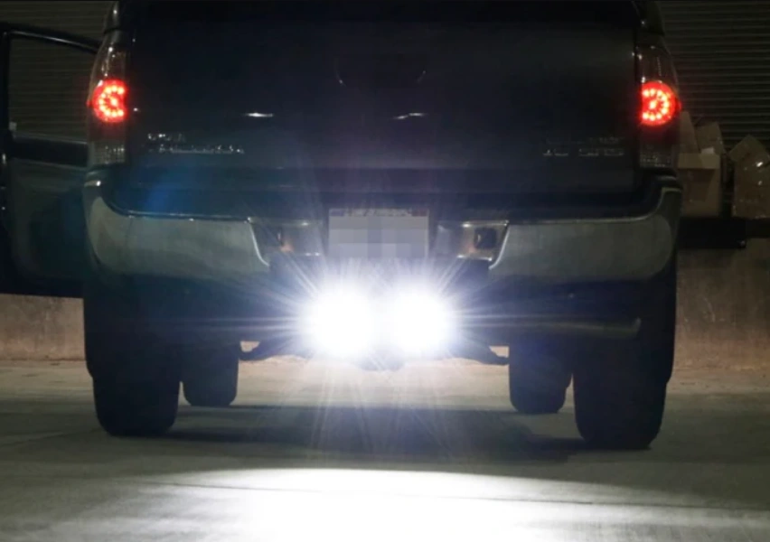 Rear view of a pickup truck at night with bright white reverse lights illuminated