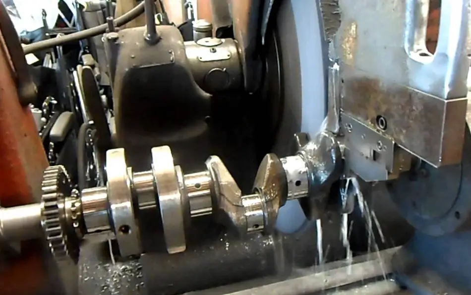 A grinding machine finishing the surface of a metal shaft