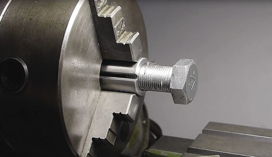 Bolt secured between chuck jaws on a conventional lathe