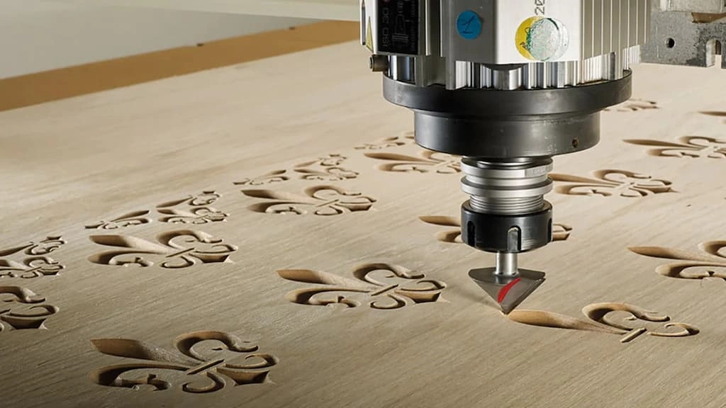 A close-up view of a CNC router bit engraving a custom design on the wood 