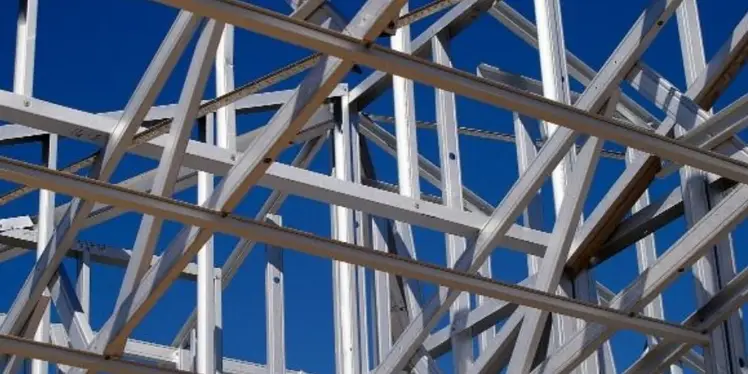 Mild steel structural framework with galvanized metal beams and cross-bracing against a clear blue sky
