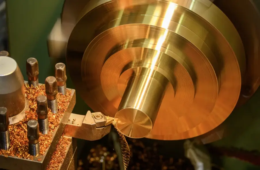 CNC lathe machining copper workpiece with cutting tool producing metal chips