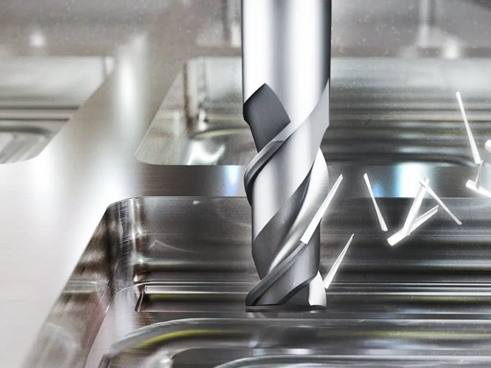 Spiral end mill cutting aluminum with metal shavings on the CNC machine table.