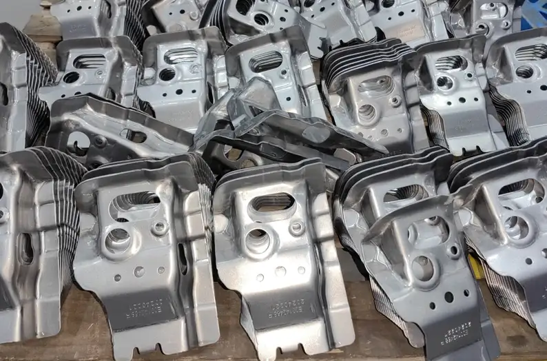Batch of deep-drawn aluminum automotive parts with cooling fins and mounting holes