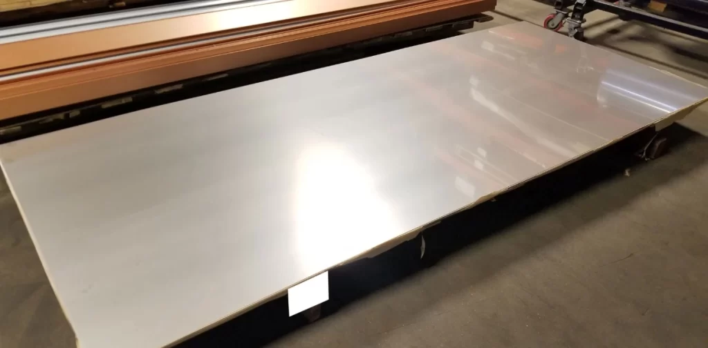 Galvanized steel sheets with a smooth reflective surface on an industrial cutting table