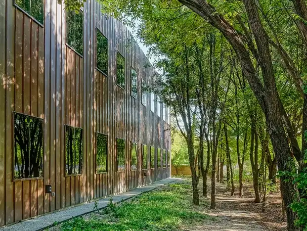 Corrugated copper sheet metal fabricated cladding on a modern building surrounded by trees