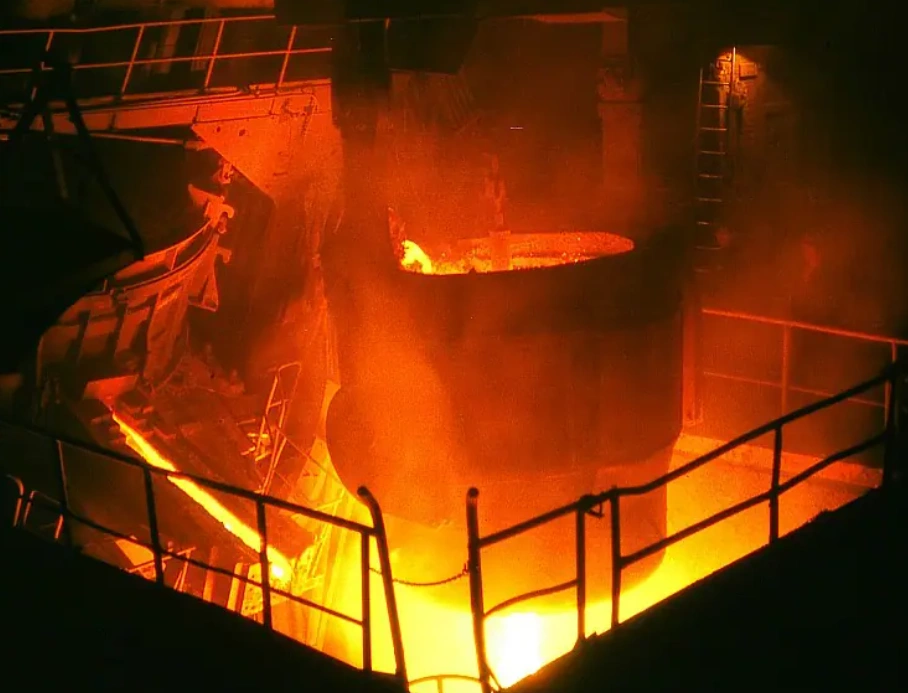 Molten metal being poured into an industrial furnace during the heat treatment process