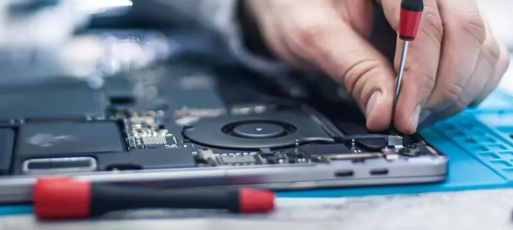 Technician repairing laptop with precision screwdriver and threaded fasteners 