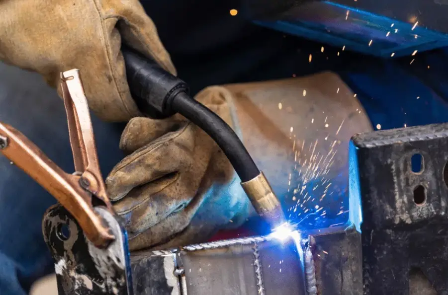 A person welding sheet metal pieces together with a blue flame, showing
