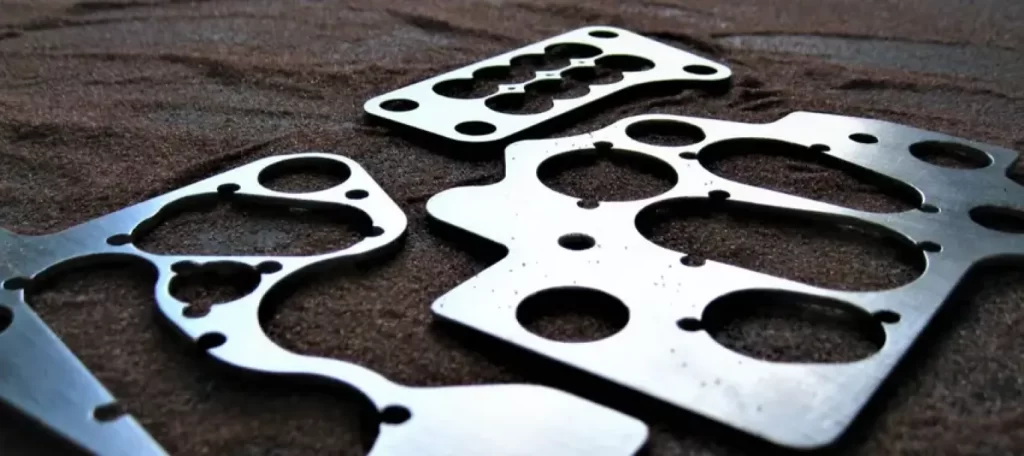Automotive metal gaskets with precision circular cutouts and bolt holes cut by abrasive waterjet technology