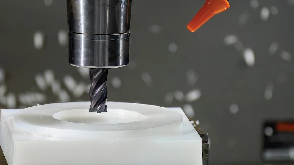 A close-up view of an end mill tool shaping the HDPE workpiece 