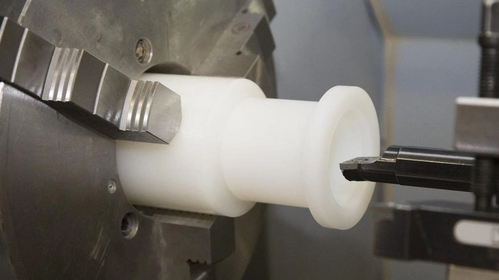 A close-up view of a turning tool shaping HDPE material on a lathe
