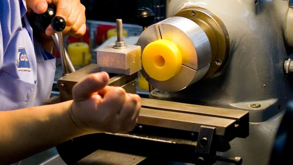 An operator moving the tool post for feeding on a lathe setup.