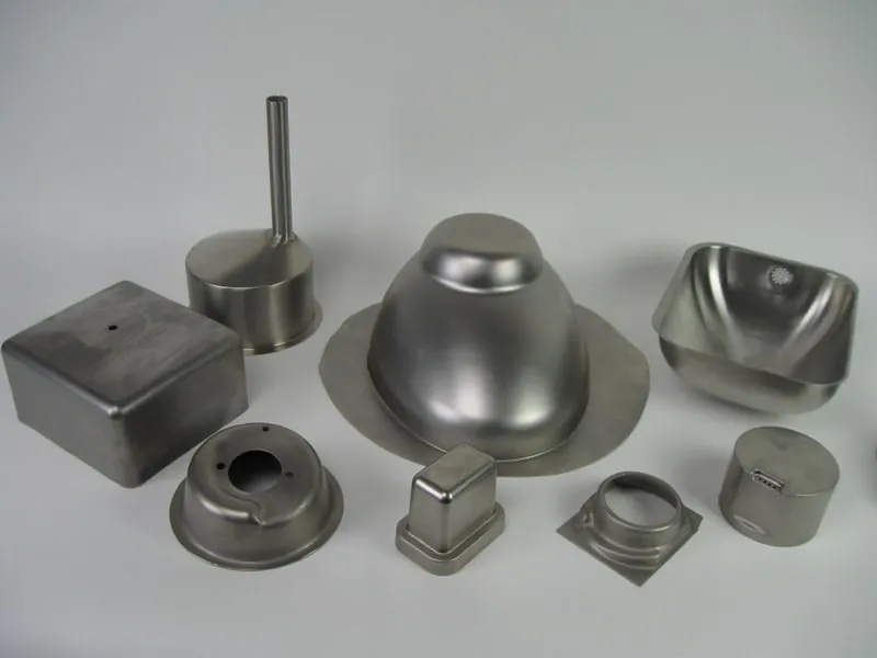 Collection of finished hydroformed metal parts in various shapes including domes, boxes, and curved components with smooth metallic surfaces