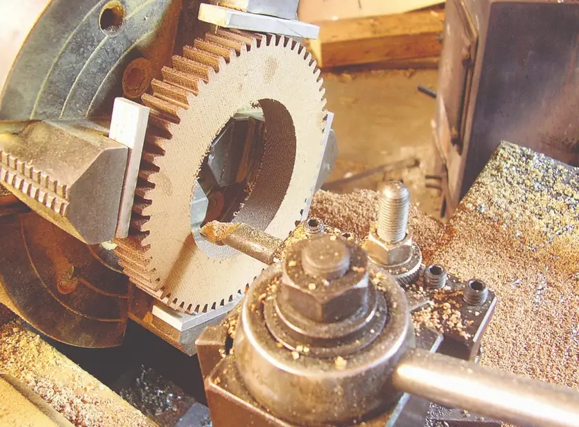 Phenolic gear being machined on a lathe with a cutting tool and chips