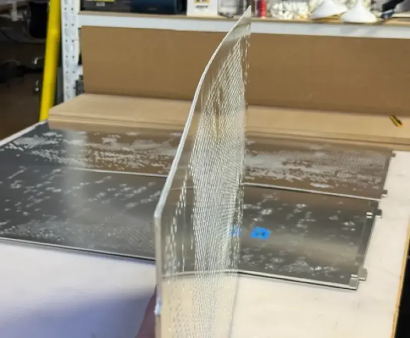 Aluminum mesh panel bent and warped in a workshop setting