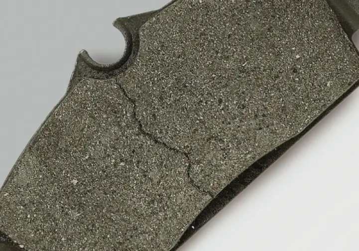 Cracked CNC-machined silicon carbide brake pad showing fracture damage and granular ceramic texture