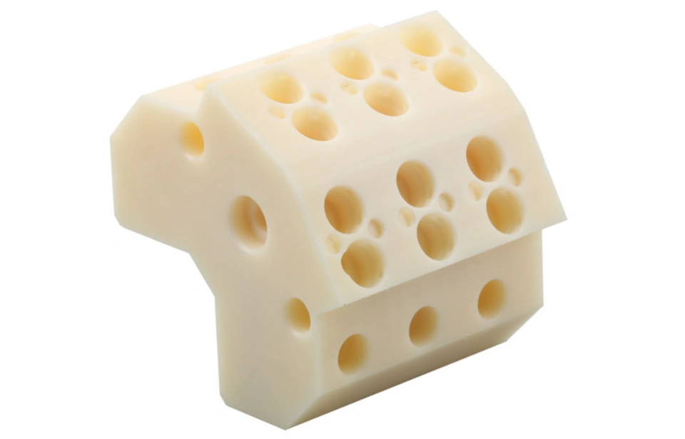 Cream-colored ABS plastic component with multiple drilled holes showing machining capabilities
