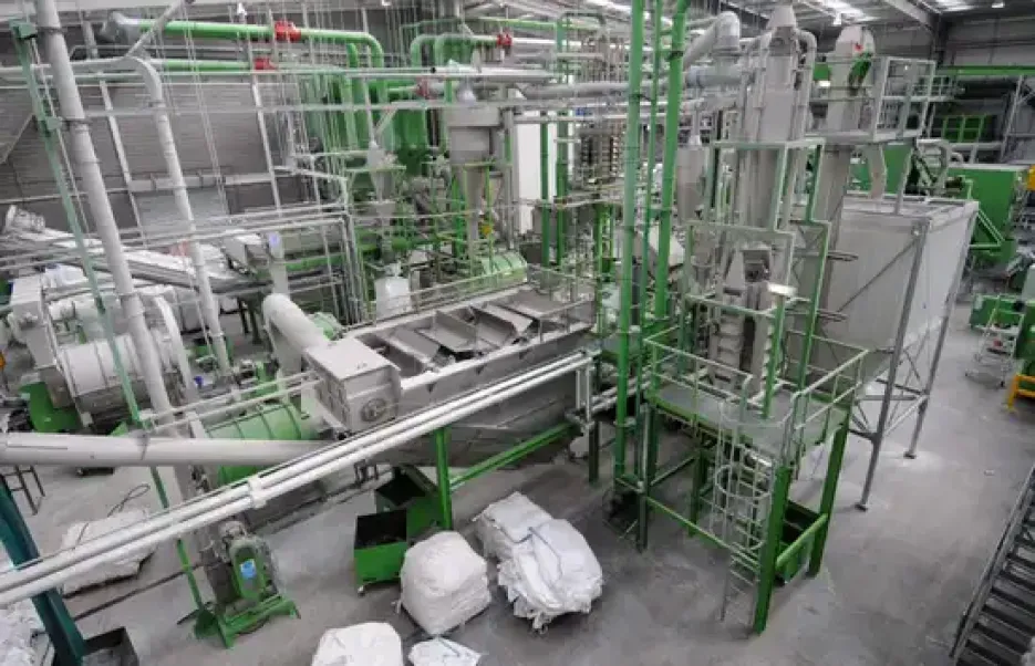 Industrial HDPE plastic recycling facility with green processing equipment and white baled material