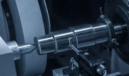 Polished steel shaft being machined on a lathe between centers