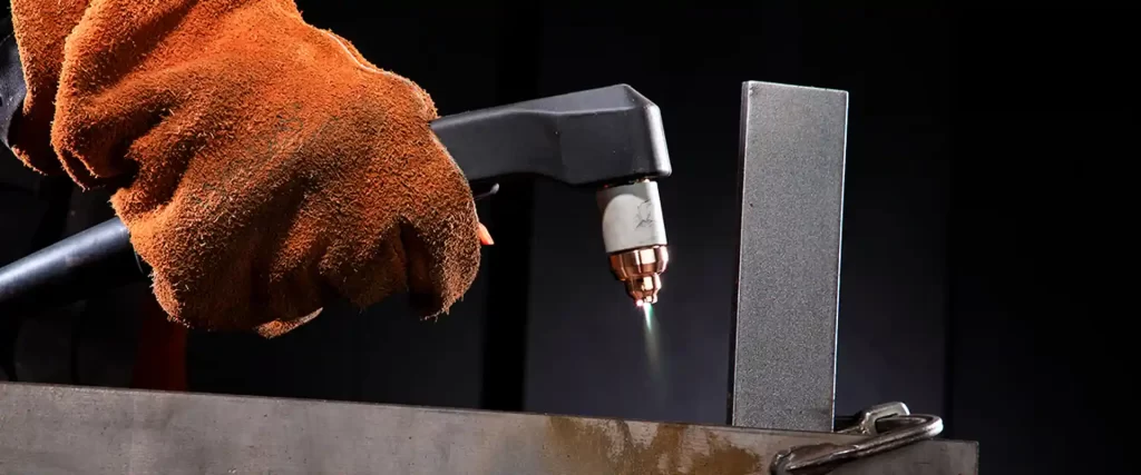 A skilled operator uses a handheld air plasma cutter to cut an aluminum sheet.