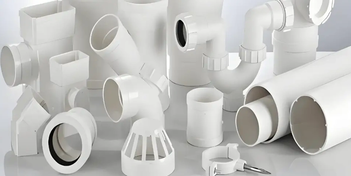 White PVC injection-molded plumbing fittings, including elbows, couplings, tees, traps, downspouts, and drainage components