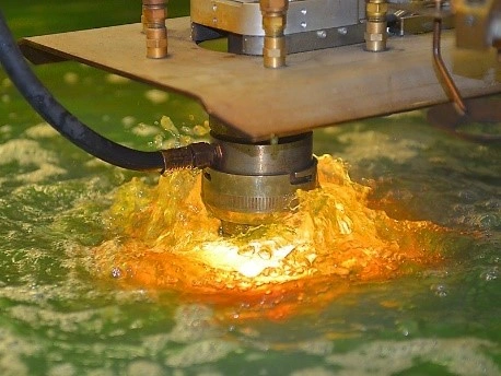 A close-up of a CNC plasma cutter cutting an aluminum sheet on a water table.