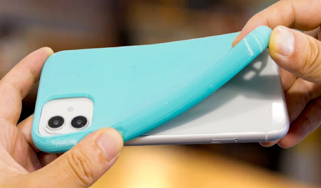 Flexible TPU injection molded smartphone case in turquoise and clear, showing elastic material being bent by hands