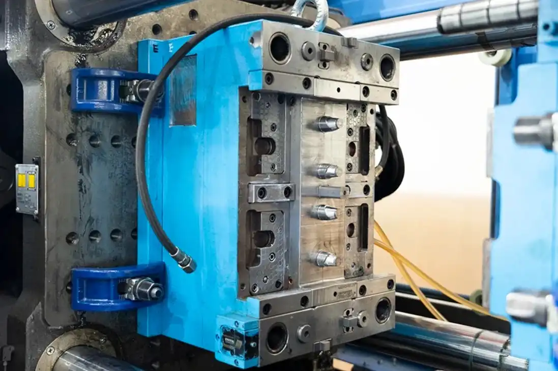 Industrial thermoplastic injection molding machine with open steel mold showing multi-cavity tooling and blue hydraulic clamping system