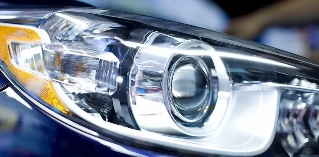 Clear polycarbonate injection-molded automotive headlight lens with projector beam housing and amber turn signal reflector
