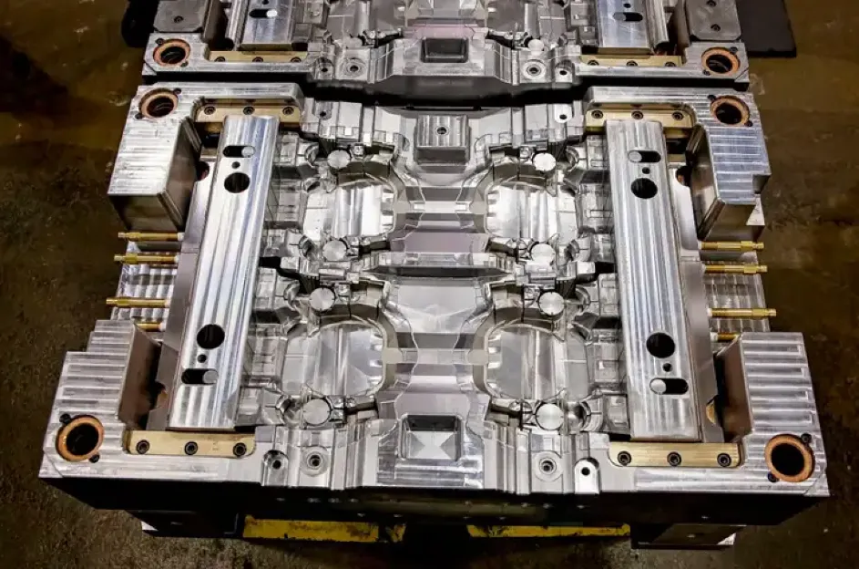 Two-shot overmolding injection mold with multi-cavity aluminum tooling showing rotating turret stations and cooling lines