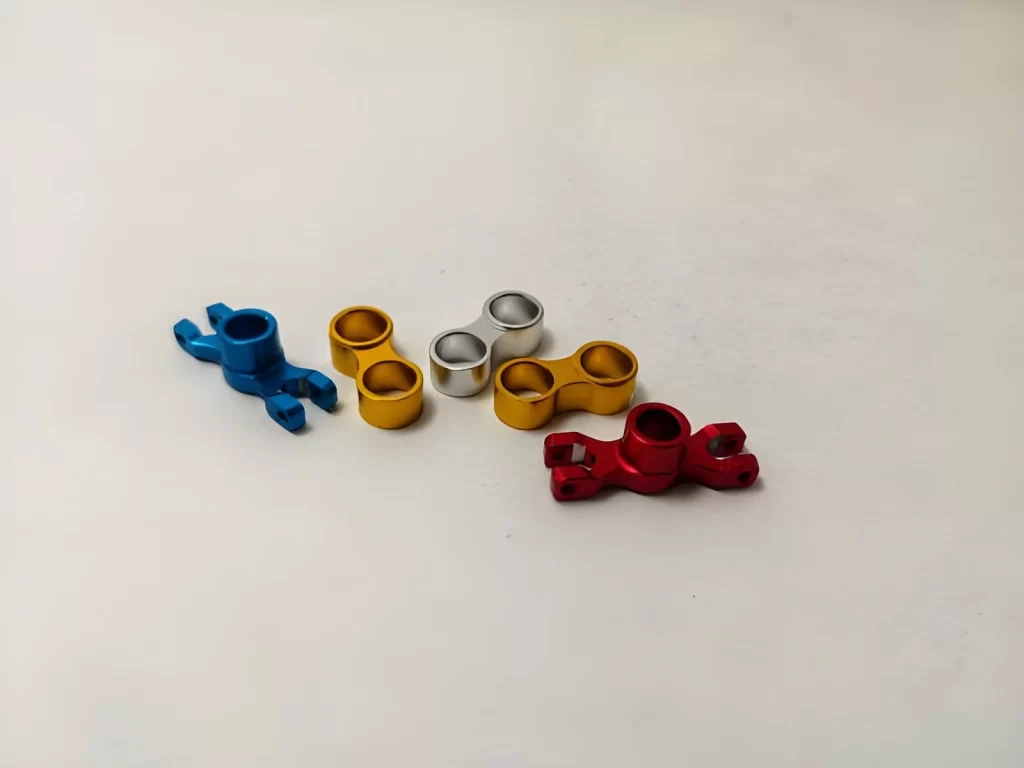 The image shows CNC-machined, anodized aluminum parts with a smooth, finished, vibrant-colored surface.