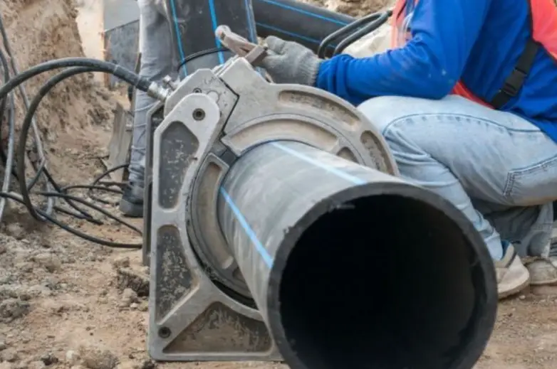 Plumber installing HDPE pipe using butt fusion welding equipment for plumbing application