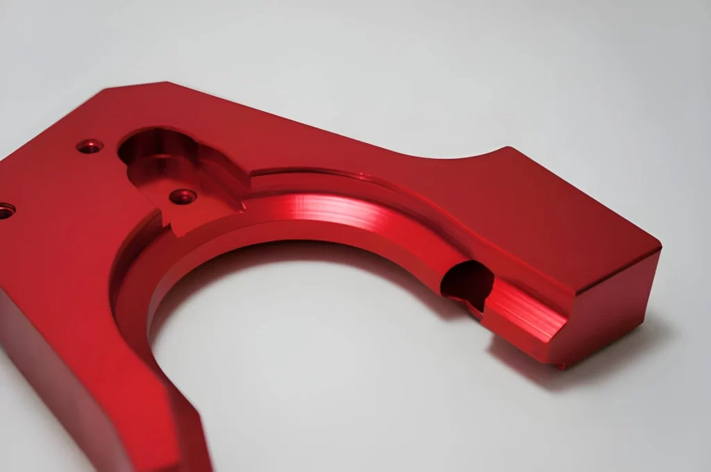 The image shows a red-colored anodized aluminum part with a uniform surface finish.