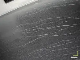 Microscopic view of thermal crazing showing fine spider-web cracks on a hardcoat anodized surface caused by thermal expansion stress.